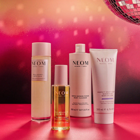 NEOM bath & body products on a pink surface with a disco ball in the background