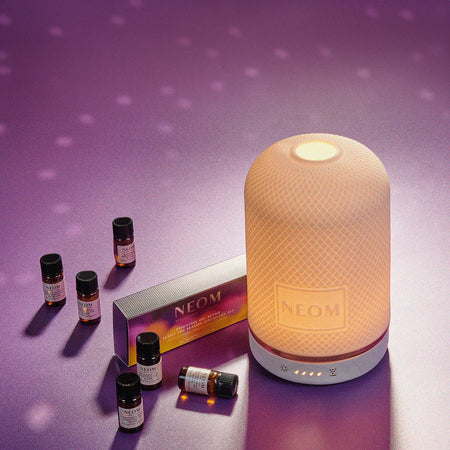 Neom electric diffuser and natural essential oils on a purple background