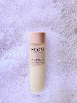 NEOM bath foam bottle on a textured gray background