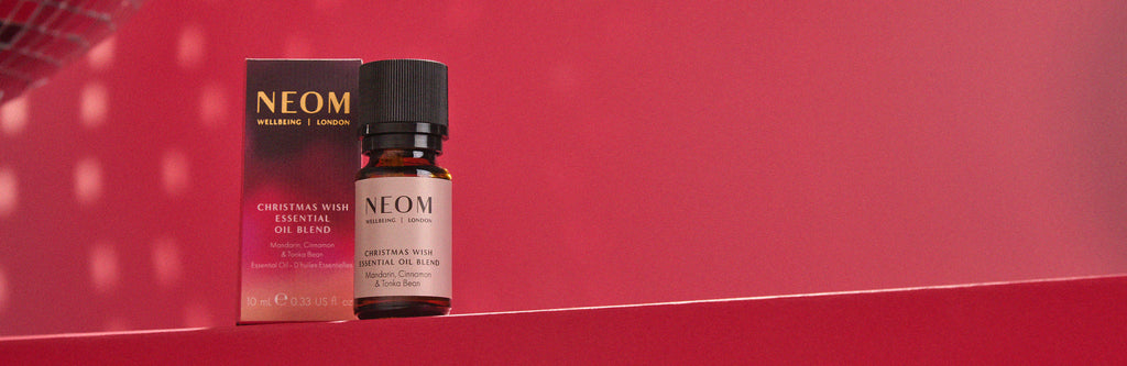 NEOM Christmas Wish essential oil bottle and packaging on a red background