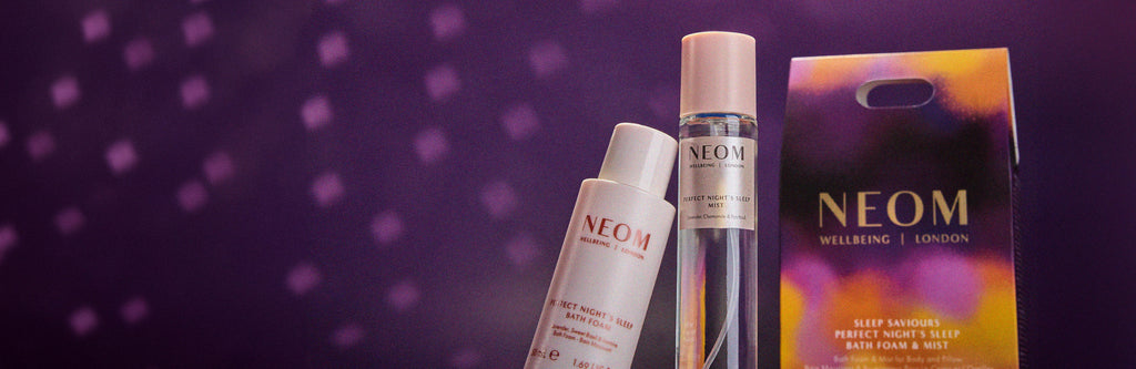NEOM skincare products including bottles and a box on a purple background