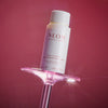 NEOM bottle on a pink stand against a red background
