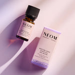 NEOM Bedtime Hero essential oil blend bottle beside its product box on a softly lit background.