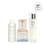 NEOM skincare products including bath foam, bath milk, and candle on a white background