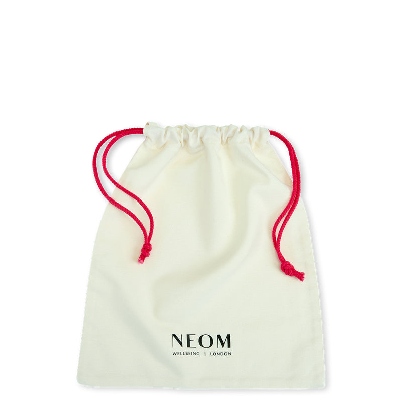 White drawstring bag with red strings and 'NEOM' branding on a white background