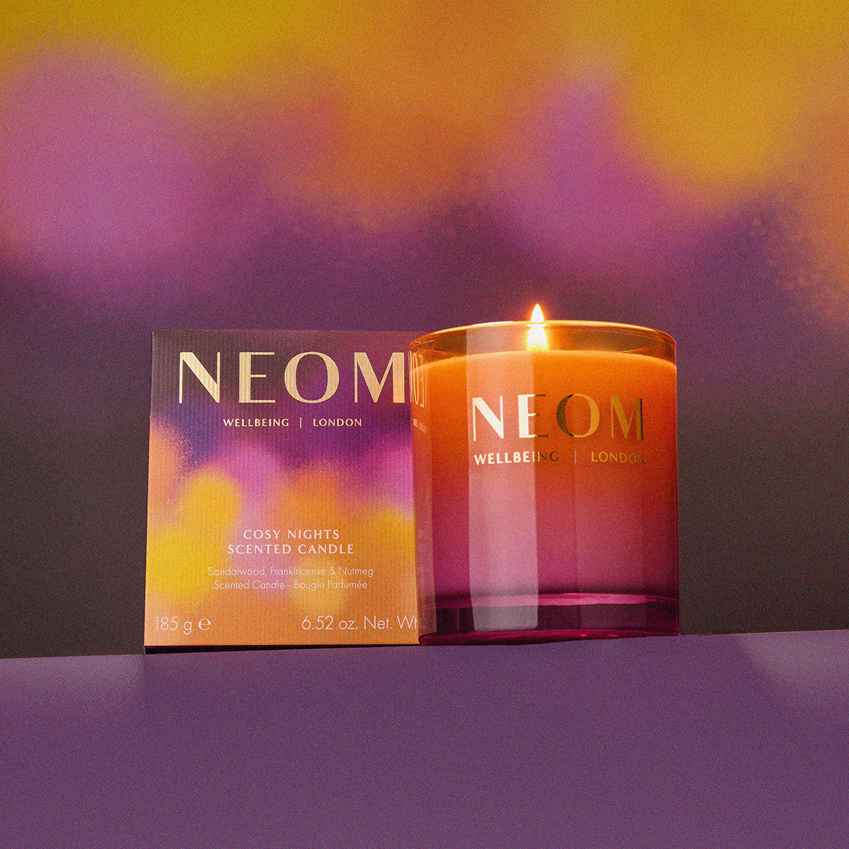 NEOM candle and packaging on a purple background