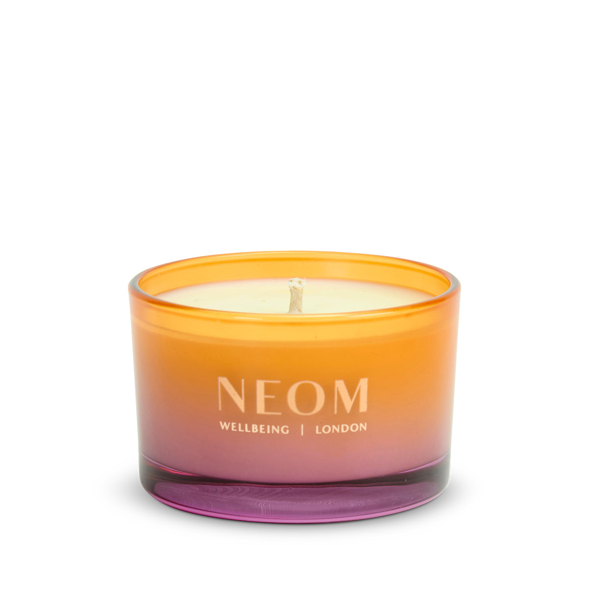 NEOM candle with gradient orange to pink design on a white background