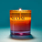 NEOM candle with a gradient color on a blue background