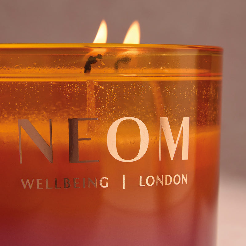 NEOM Cosy NIghts candle with flames on a neutral background