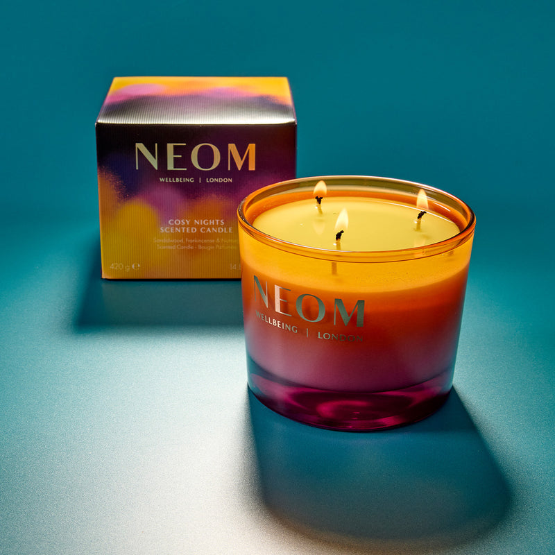 NEOM candle with packaging on a blue background