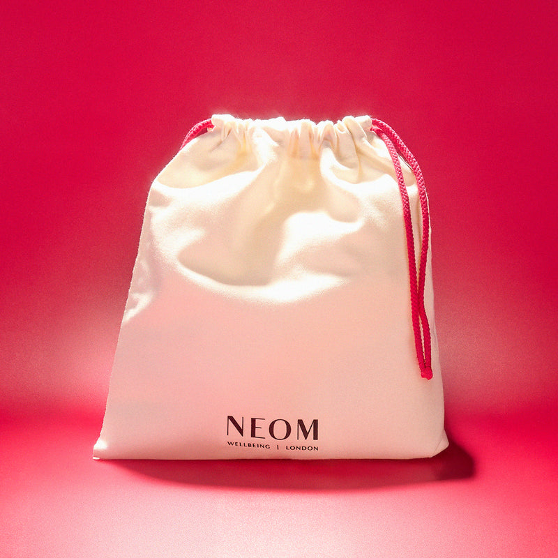 NEOM drawstring bag on a red background
