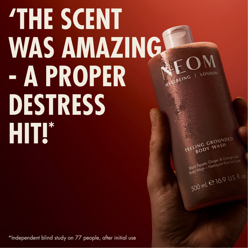 “Hand holding NEOM Feeling Grounded Body Wash against a red background. Large text reads: ‘The scent was amazing – a proper destress hit!’ Small print: ‘*Independent blind study on 77 people, after initial use.’”