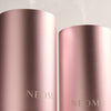 Two rose gold NEOM diffusers on a light gray background