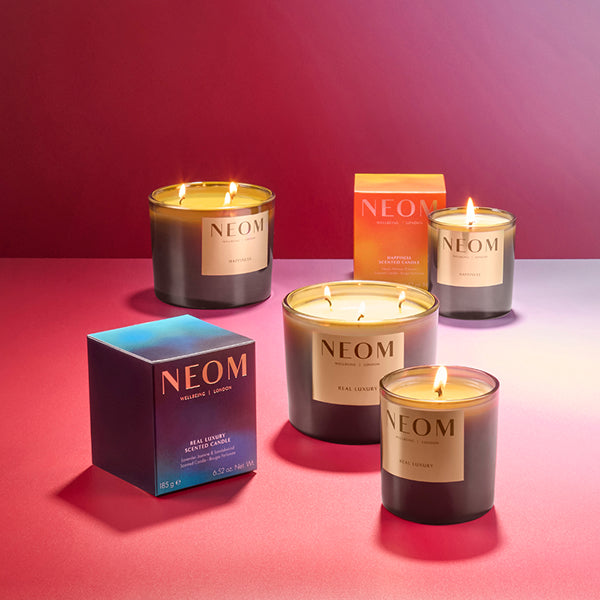 NEOM candles and boxes on a pink background