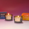 Two NEOM candles with their packaging on a pink background