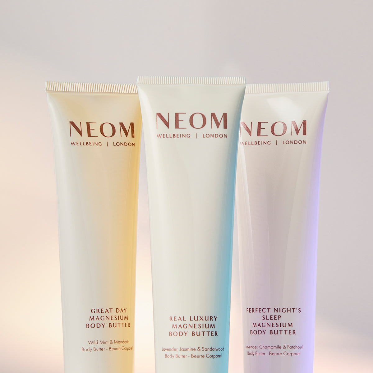 Three NEOM body butters on a gradient background