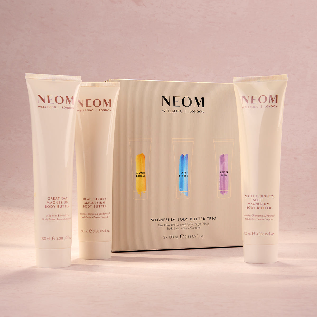 Three NEOM body butters on a pink background