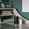 Neom products on a desk with a shelf in the background