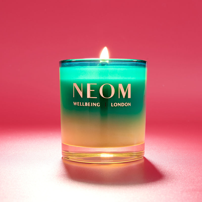 NEOM candle with a gradient design on a red background