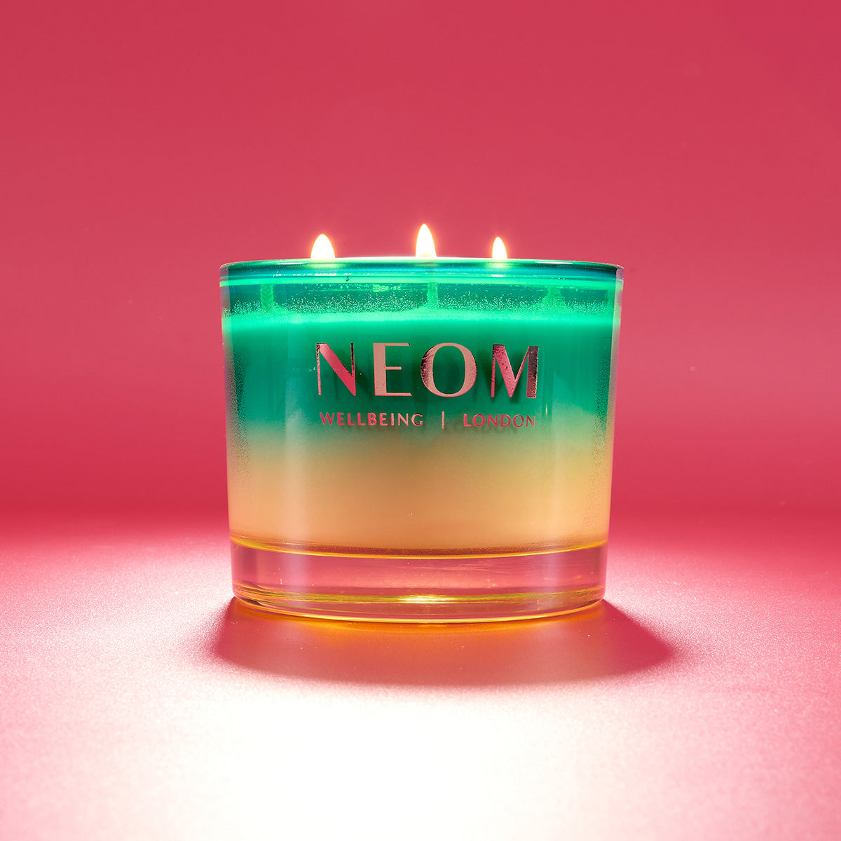 NEOM candle with a gradient design on a pink background