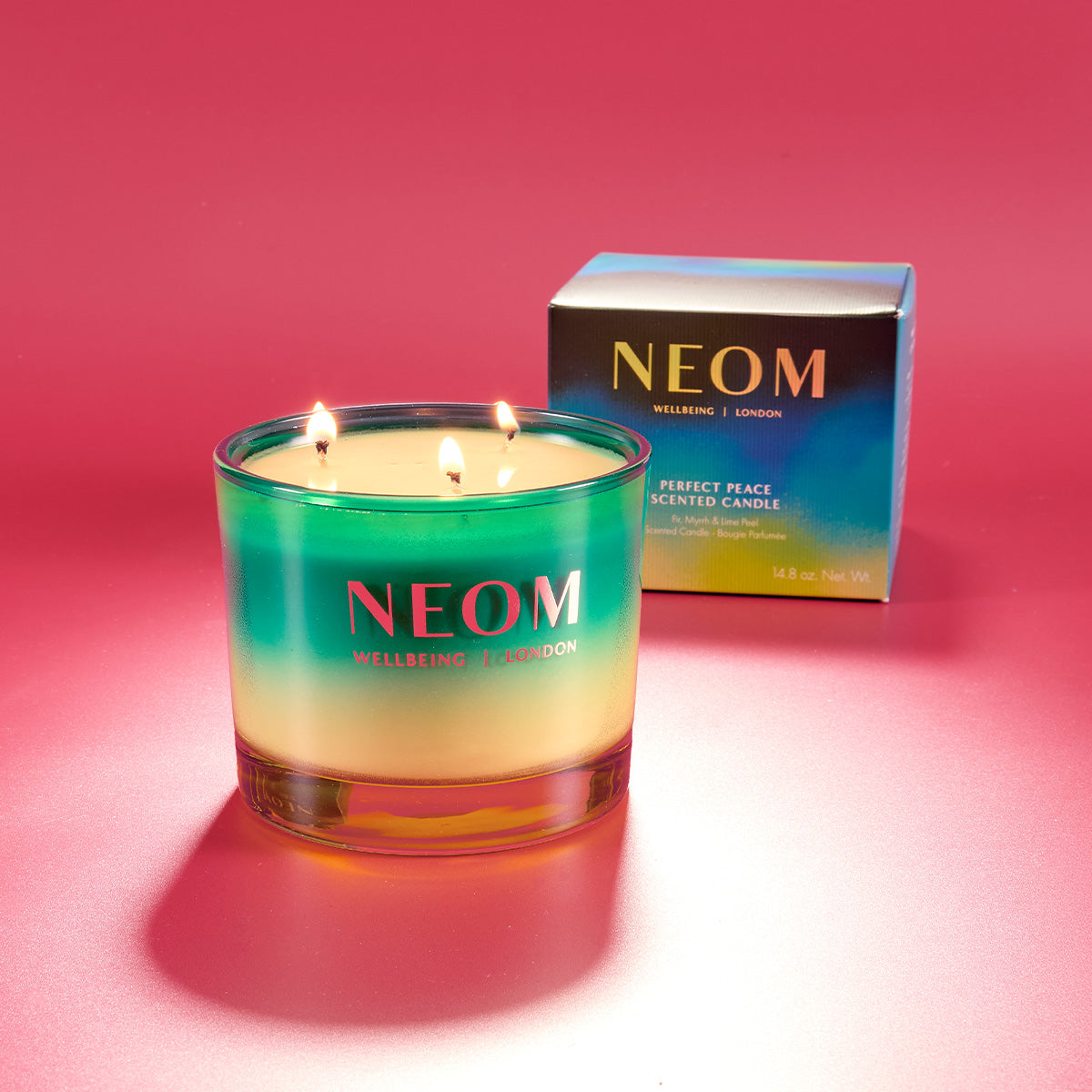 NEOM scented candle with a box on a pink background