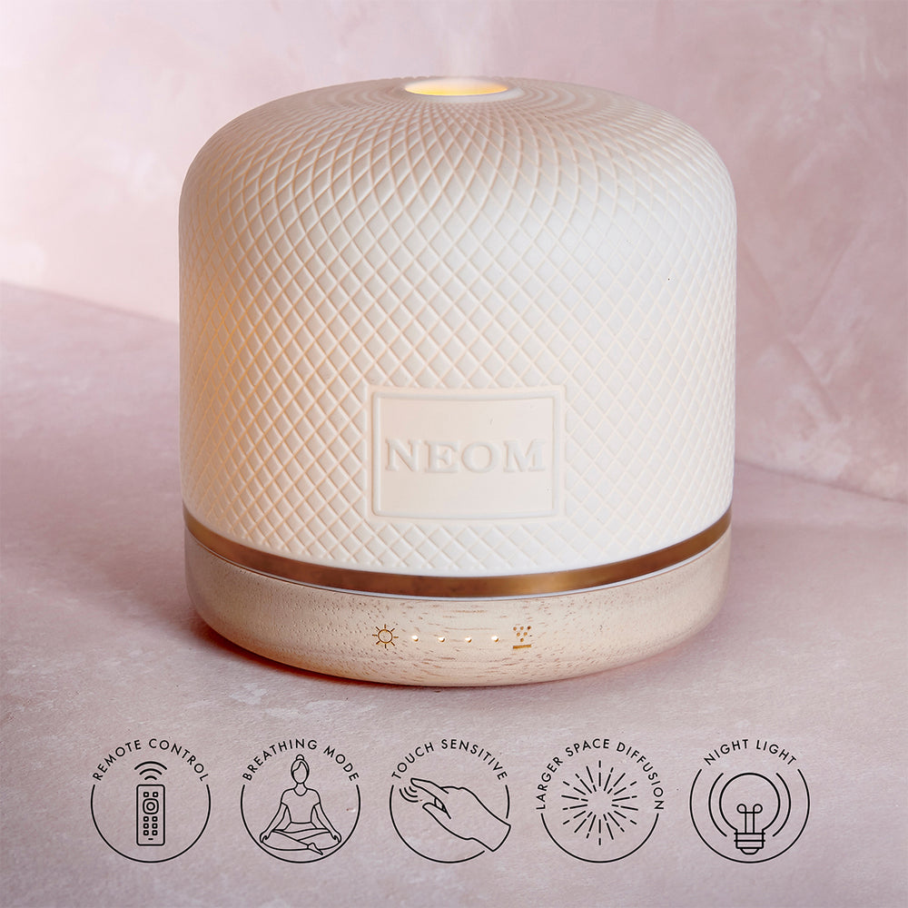 Neom diffuser on a soft pink background with feature icons below.