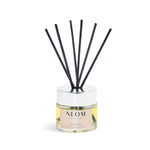 NEOM diffuser with black sticks on a white background