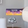 Hand holding NEOM Scent the Season Discovery Set box with essential oil blends and silver disco balls.