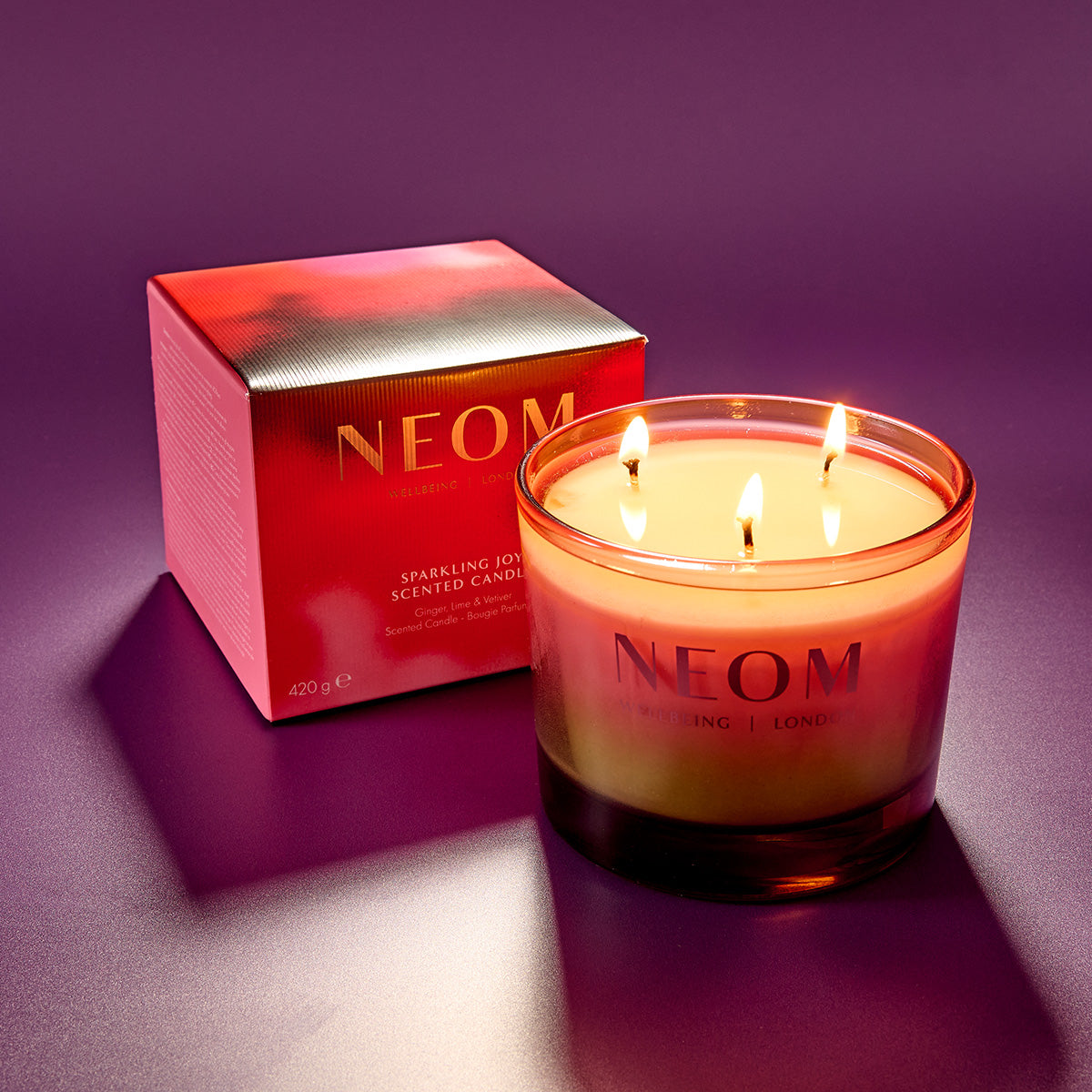 NEOM scented candle with packaging on a purple background