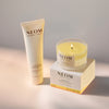 NEOM great day magnesium body butter and happiness travel candle on a neutral background