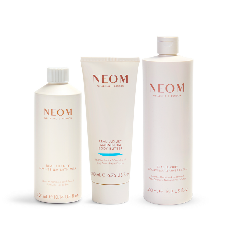NEOM skincare products including a bath milk, body butter, and cream on a white background