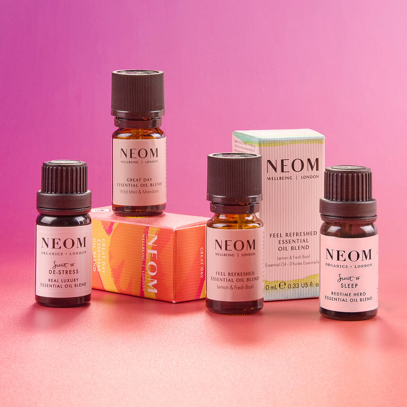 NEOM essential oil bottles and packaging on a pink background