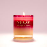 NEOM candle with a gradient color design on a light pink background