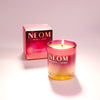 NEOM scented candle with packaging on a light pink background